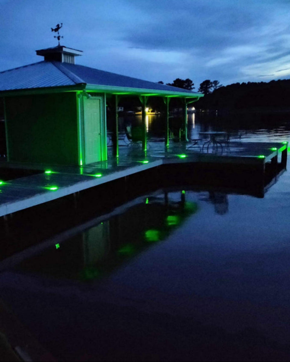 dock with green lights on a lake at night